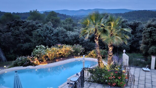 Une piscine offrant une vue sur le paysage environnant, notamment les arbres et les collines.