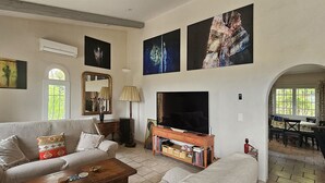 Un salon avec un canapé, une table basse, un téléviseur et des œuvres d’art accrochées aux murs.