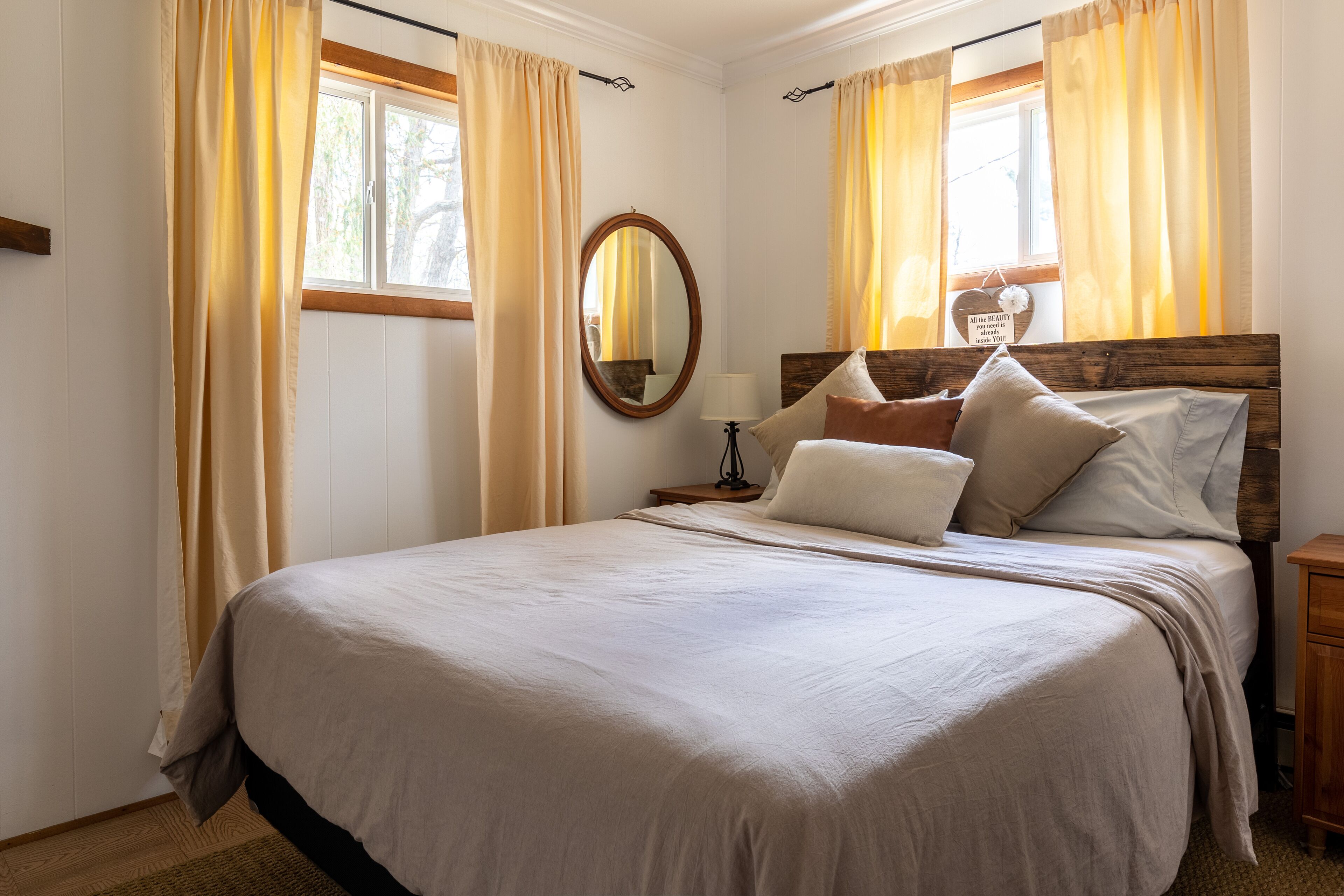 A bedroom with a large bed, wooden headboard, and a nightstand with a lamp.