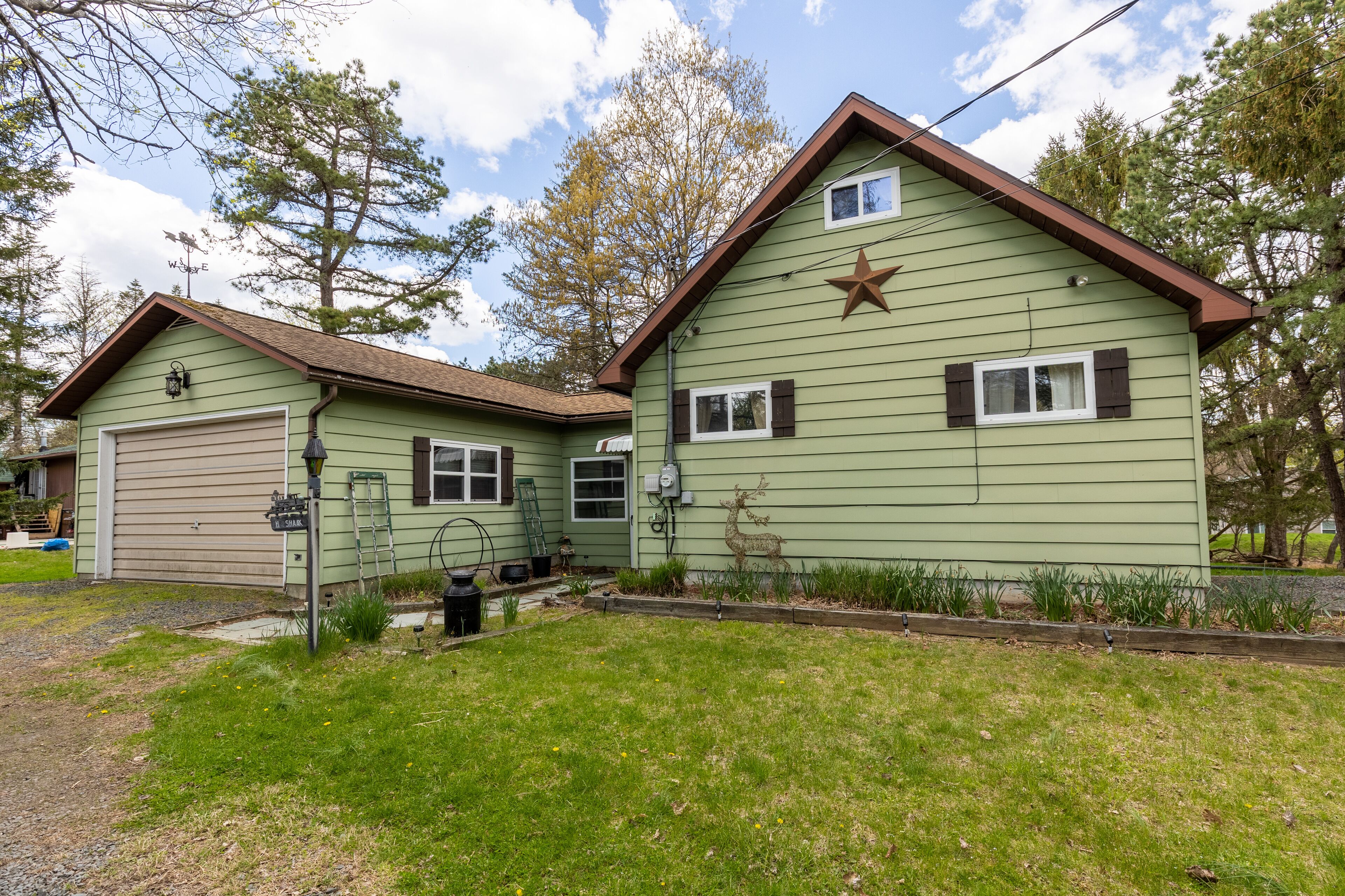 A two-story house with a garage, a star decoration on the front, and a deer statue.
