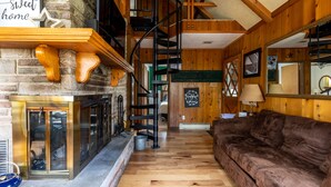 Un interior acogedor con chimenea, paredes de madera, una escalera y un sofá cómodo.