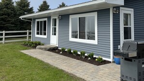 Ein zweistöckiges Haus mit Veranda, Garage und Grill im Einfahrtsbereich.