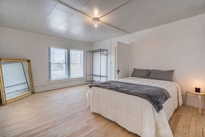 Cozy retreat with a large bed, wooden floor, and a window with blinds.