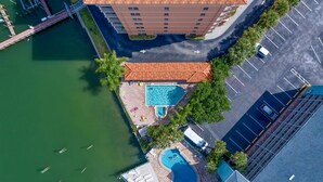 An aerial view of a hotel with a swimming pool, a dock, and a parking lot.