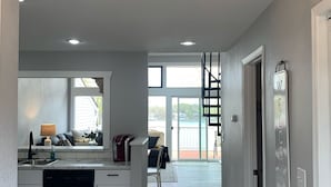 Una cocina moderna con una araña, un comedor con vistas y una escalera que lleva a un balcón.