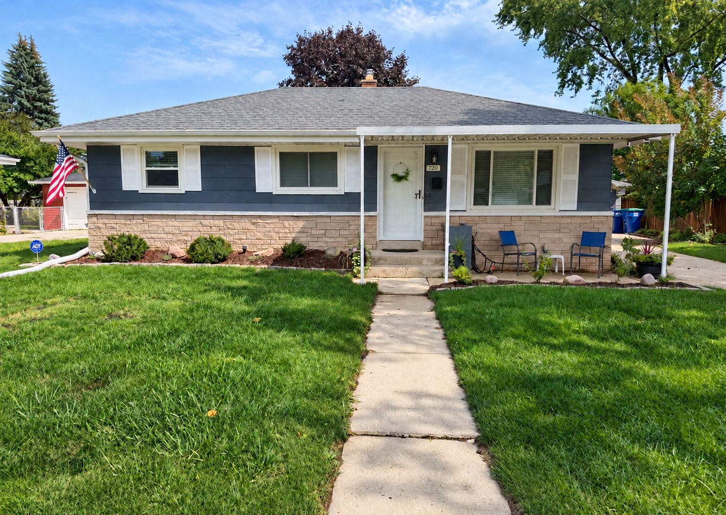 A single-story house with a front porch, a mailbox, and a small garden.