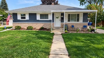 A single-story house with a front porch, a mailbox, and a small garden.
