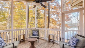 A covered porch with wooden flooring, a ceiling fan, and seating with patterned cushions. - The Lake House: Dock|Marine Hammock|Screen Porch (Prospect Hill)