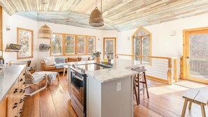 A cozy kitchen with a central island, wooden flooring, and large windows offering views of the outdoors. - The Lake House: Dock|Marine Hammock|Screen Porch (Prospect Hill)