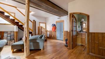 Amplia sala de estar con escalera de madera, un sofá y una puerta que da a un baño.