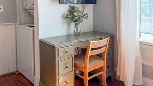 A room with a wooden desk, a television, a vase with flowers, and a window with curtains. - Studio with Deck, Walk to Duke (Durham)