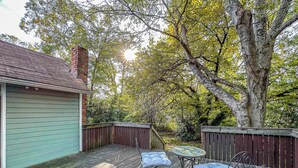 A wooden deck with a table and chairs, surrounded by a wooden fence and trees. - Studio with Deck, Walk to Duke (Durham)