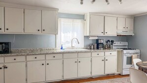 A kitchen with white cabinets, a microwave, a coffee maker, a stove, and a sink. - Studio with Deck, Walk to Duke (Durham)