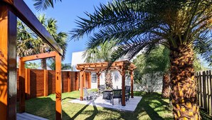 A backyard with a wooden pergola, a patio table, and chairs.