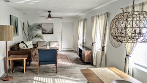 Relax in this spacious living area with a high ceiling, ceiling fan, and comfortable seating for two.