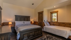 A bedroom with a large bed, two bedside tables, a wooden wardrobe, and a window with a view.