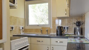 Een keuken met een raam, een fornuis, een spoelbak en kastjes.