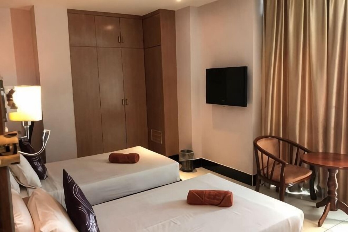 A hotel room with two beds, a TV, a desk, and a chair.