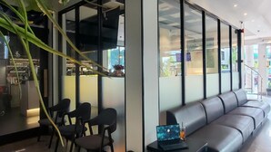 Een modern interieur met een bank, stoelen, een laptop en een glazen scheidingswand.