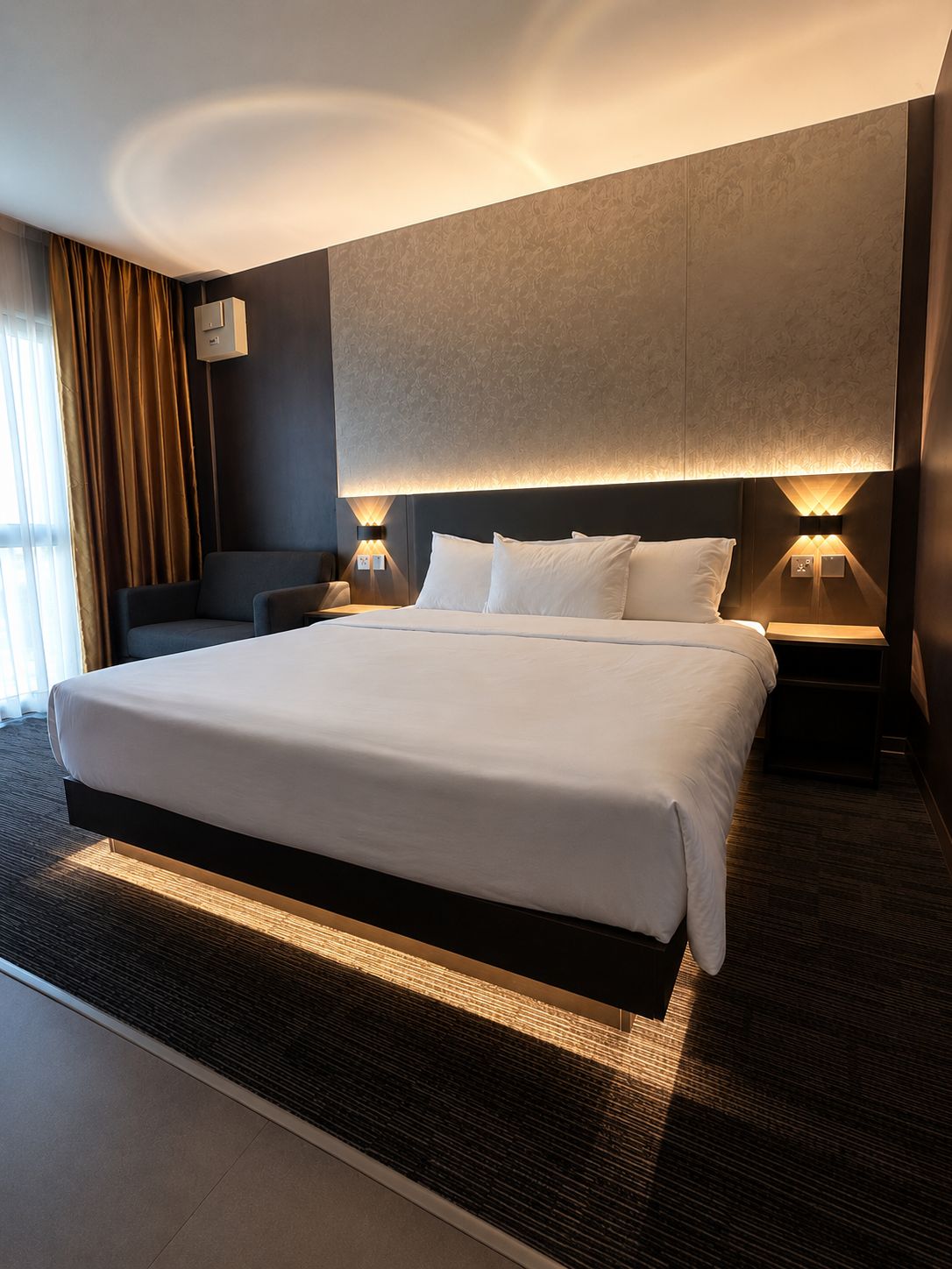 Une chambre d’hôtel moderne avec un grand lit, deux tables de chevet, une lampe fixée au mur et une vue sur l’extérieur.