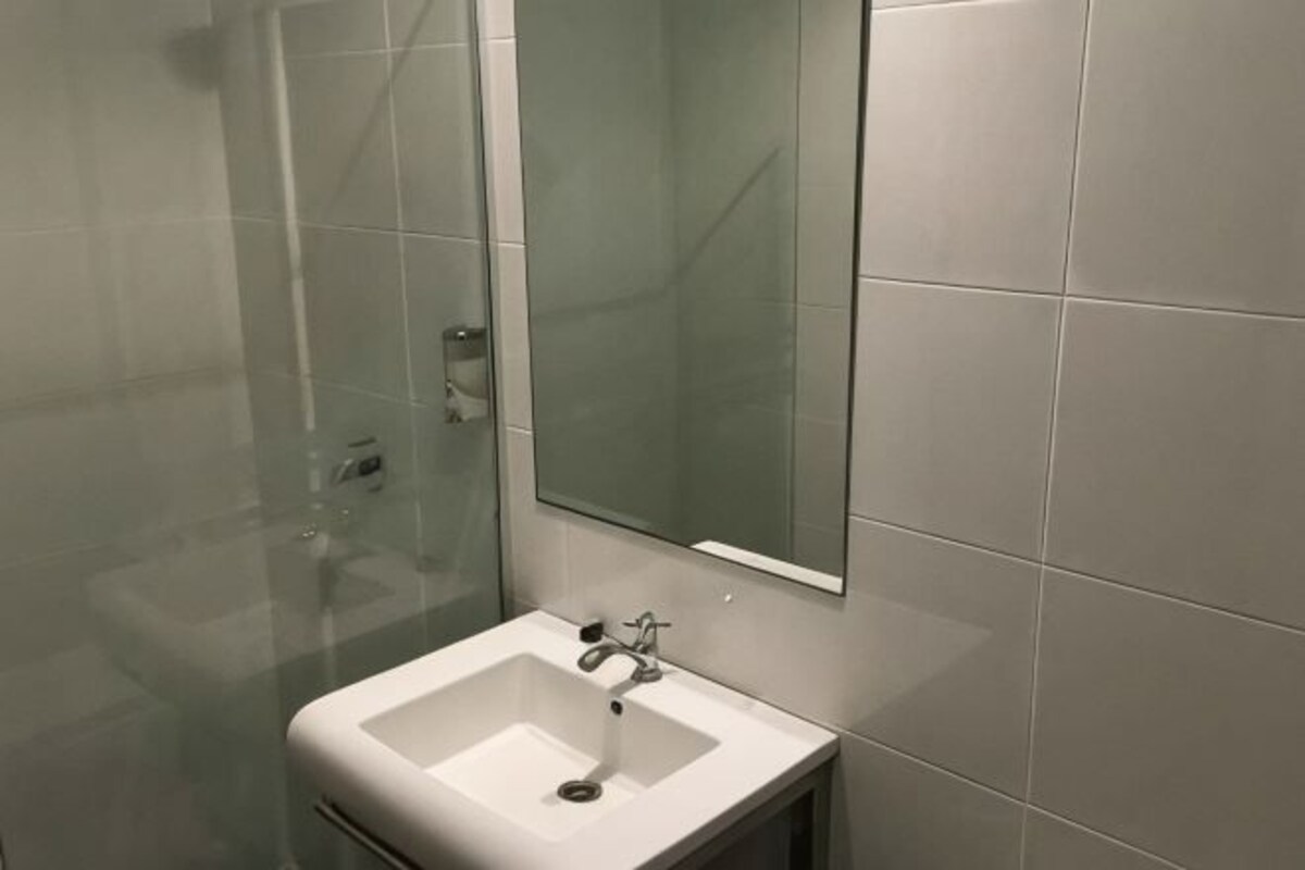 A bathroom with a glass shower enclosure, a white sink, and a mirror.