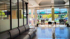 Een moderne lobby met een zithoek, grote ramen en uitzicht op buiten.