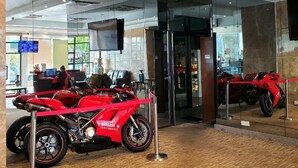 Een modern interieur met een rode motorfiets in de etalage, glazen wanden en een plafond met inbouwspots.