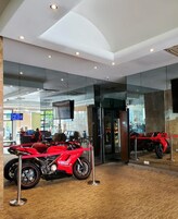 Un interior moderno con una motocicleta roja en exhibición, paredes de vidrio e iluminación empotrada en el techo.