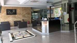 Een hotel lobby met een receptiebalie, een zithoek en een bord waarop 'the room' staat.