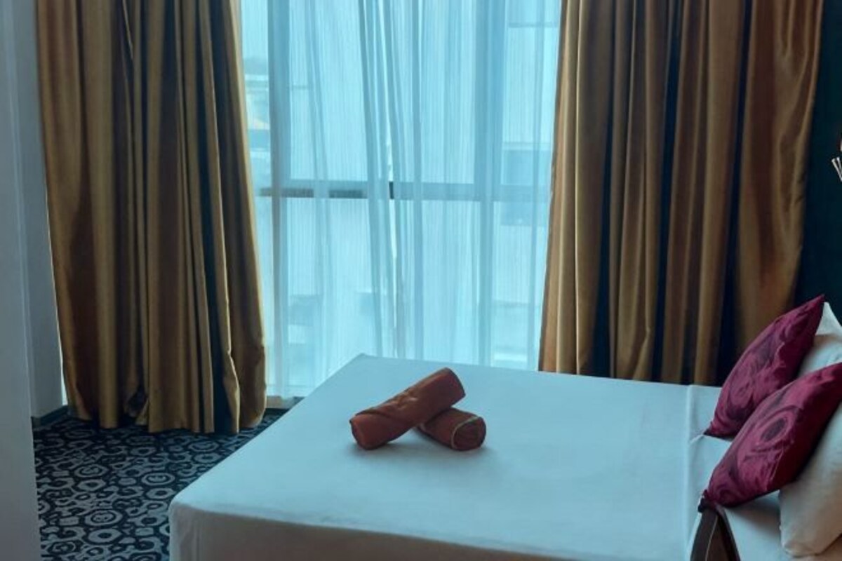 A hotel room with a bed, curtains, and a window.