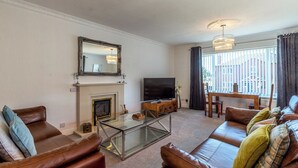 A living room with leather sofas, a glass coffee table, a fireplace, a television, and a large mirror.