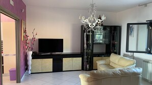 A living room with a TV, a chandelier, a sofa, and a glass cabinet. - Villa Alfonso with sea view (Siculiana)