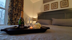 A bed with a tray containing a bottle of champagne, two glasses, and a candle.