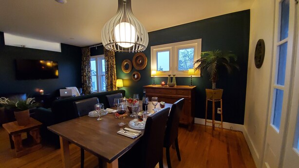 A dining area with a wooden table set for a meal, a sofa, and a TV in the background.