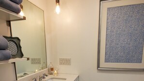 A modern bathroom with a white vanity, a large mirror, and pendant lights.