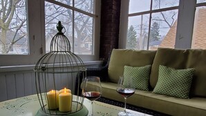 A cozy room with a green table, candles, and a glass of red wine.