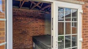 A small, enclosed outdoor area with a brick wall, a metal bench, and a small wooden table. - 2 bedroom accommodation in Bridlington (Bridlington)