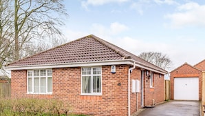 A two-story brick house with a tiled roof, a garage, and a paved driveway. - 2 bedroom accommodation in Bridlington (Bridlington)