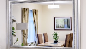 A room with a dining table, chairs, a potted plant, a framed picture on the wall, and a window with curtains. - 2 bedroom accommodation in Bridlington (Bridlington)