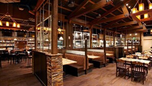 Un restaurant doté de poutres en bois, de piliers en pierre et proposant différents types de sièges, notamment des banquettes et des tables.