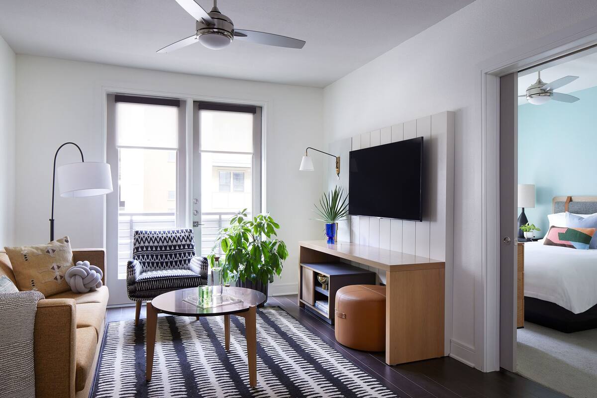 A modern living room with a sofa, armchair, coffee table, and a TV mounted on the wall.