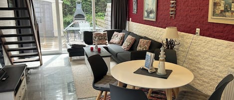 Een moderne woonkamer met een bank, salontafel en stoelen, een trap en uitzicht op de omgeving.