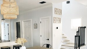 Une cuisine moderne avec une table et des chaises en bois, un luminaire suspendu et un escalier avec des rampes noires.