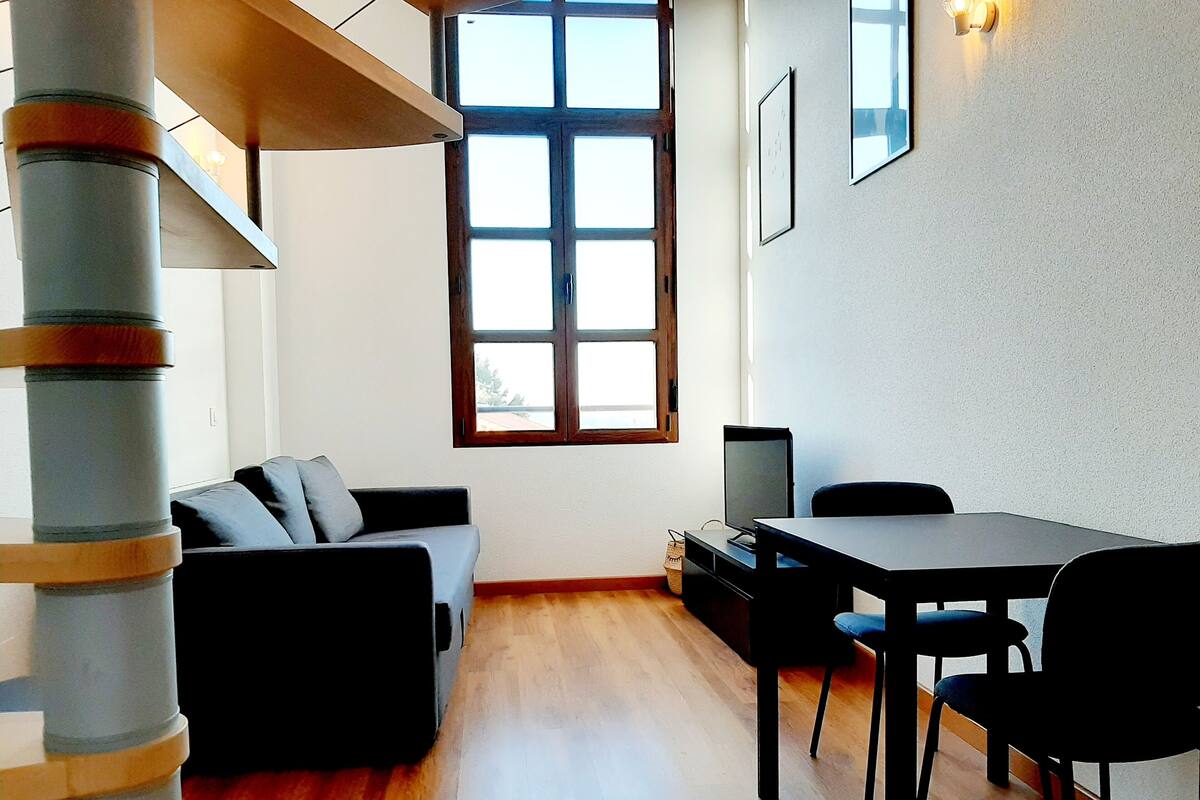 A modern living room with a sofa, a dining table, and a TV.