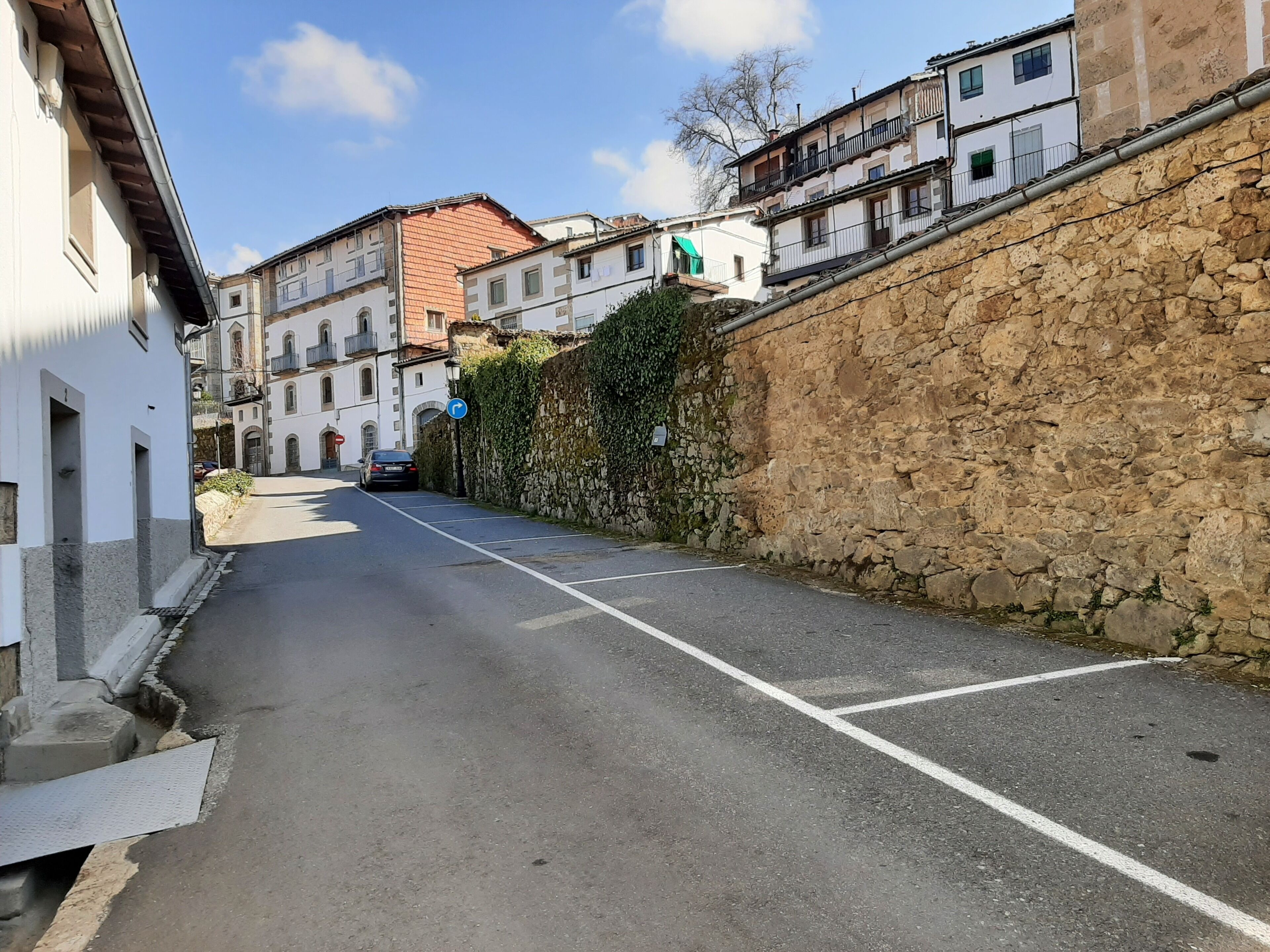 Una estrecha calle flanqueada por muros de piedra y edificios de arquitectura tradicional.