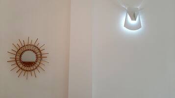 A wall with a circular wooden art piece and a light fixture with a geometric design.