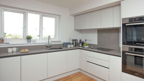 Una cocina moderna con armarios blancos, un lavamanos de acero inoxidable y un horno.