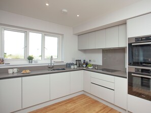 A modern kitchen with white cabinets, a stainless steel sink, and an oven. - 5 bedroom accommodation in Crantock, near Newquay (Crantock, near Newquay)