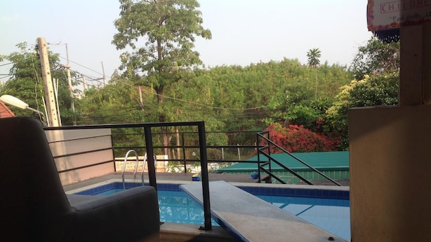 Un área de piscina con una silla, una piscina pequeña y una escalera que lleva a una terraza.