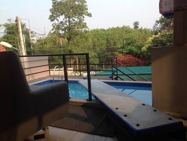 Uma área de piscina com cadeira, piscina pequena e escadaria para um deck.